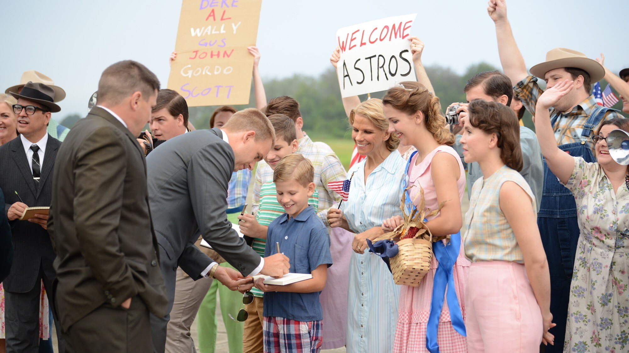 Gus Grissom played by Michael Trotter and John Glenn played by Patrick J. Adams greet fans and sign autographs in an effort to win the hearts and minds of Americans in National Geographic's THE RIGHT STUFF streaming on Disney+.