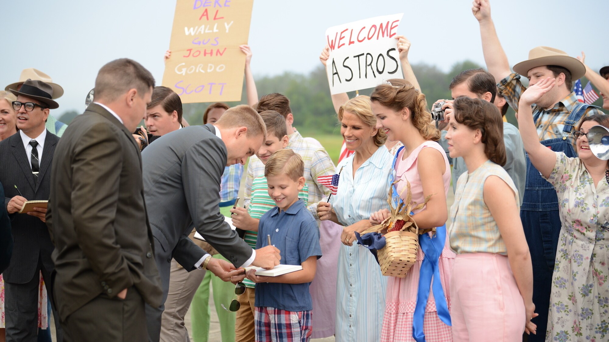 Gus Grissom played by Michael Trotter and John Glenn played by Patrick J. Adams greet fans and sign autographs in an effort to win the hearts and minds of Americans in National Geographic's THE RIGHT STUFF streaming on Disney+. 