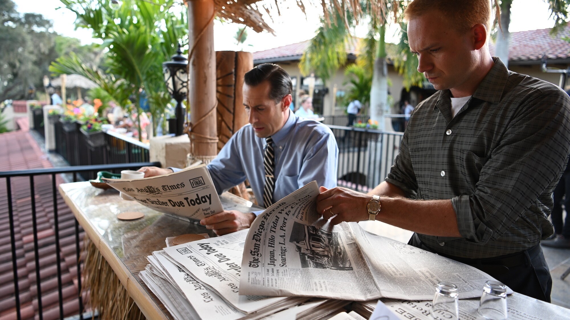 L to R: LIFE Magazine reporter Loudon Wainwright played by Josh Cooke reads the newspaper while John Glenn played by Patrick J. Adams examines it for a scandal involving a Mercury astronaut in National Geographic's THE RIGHT STUFF streaming on Disney+. (National Geographic/Gene Page)