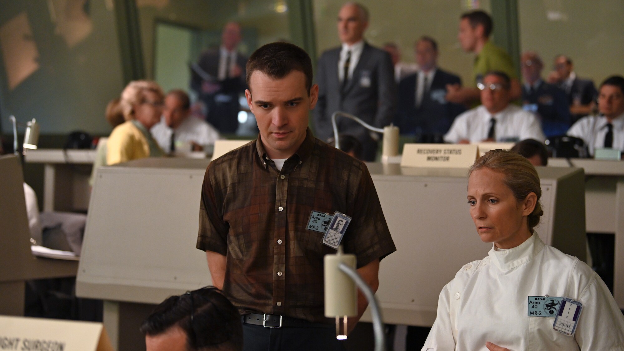 Micah Stock as Deke Slayton (front center) in Mercury Control Center during crucial rocket launch carrying a chimpanzee in National Geographic's THE RIGHT STUFF streaming on Disney+. (National Geographic/Gene Page)