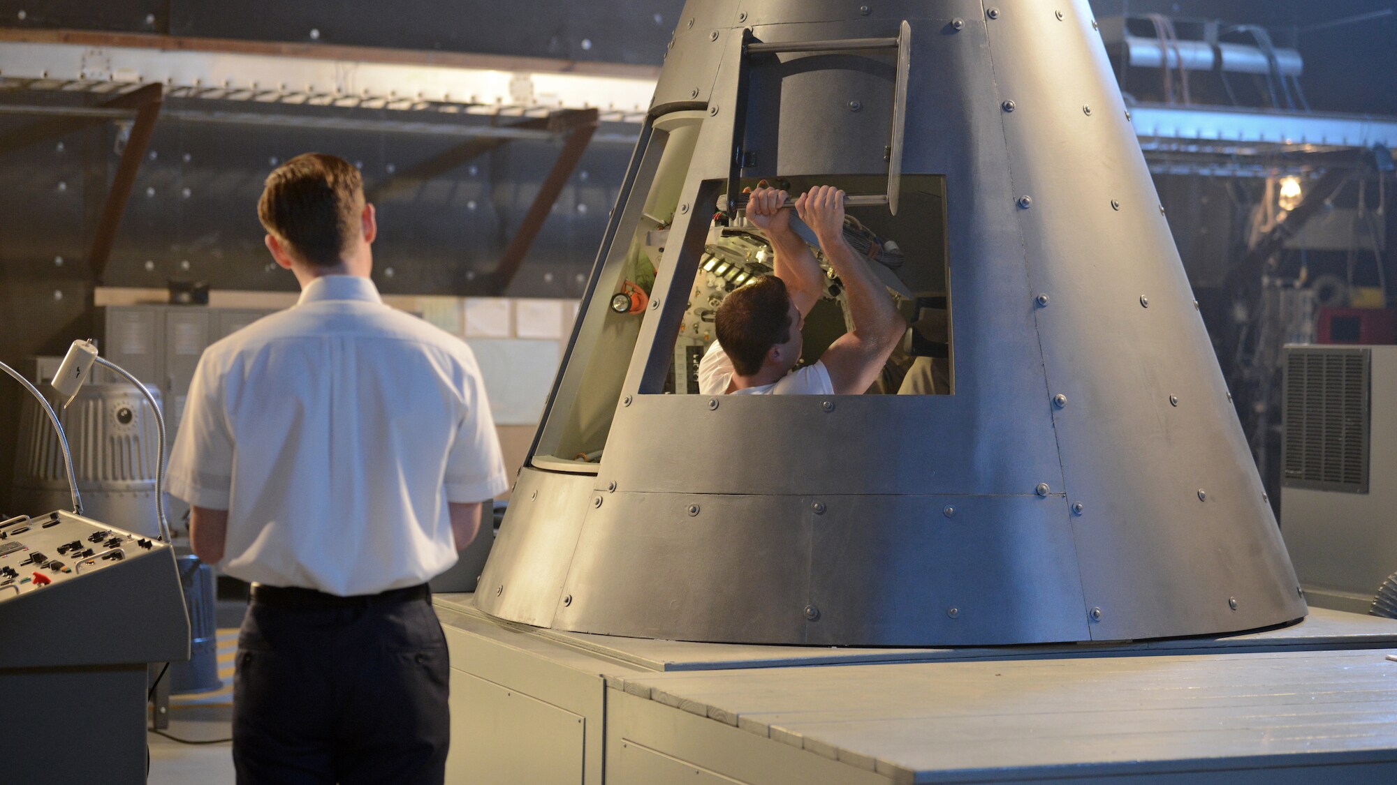 Glynn Lunney (L) played by Jackson Pace stands by while Alan Shepard played by Jake McDorman enters the trainer capsule during a practice session in National Geographic's THE RIGHT STUFF. (Credit: National Geographic/Gene Page)