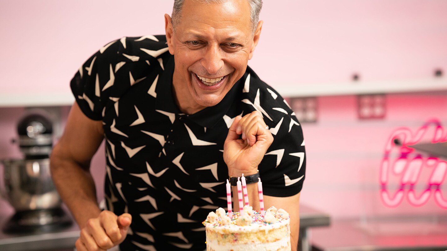 Jeff Goldblum smiling whilst looking at a birthday cake