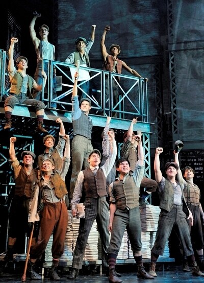 The cast of Newsies performing on stage, fists raised in protest