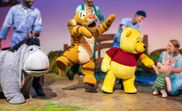 Winnie the Pooh, Tigger, Eeyore and Piglet puppets all on stage in movement.