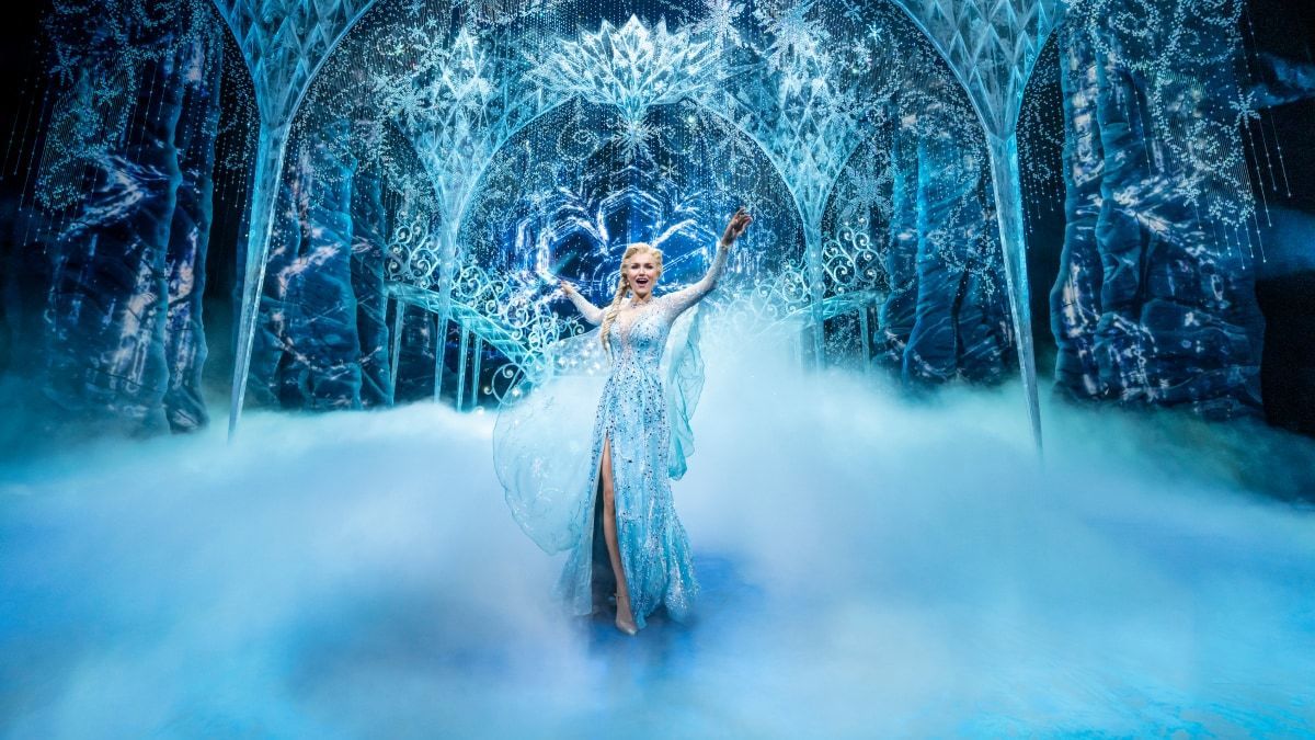 Elsa standing in front of her Ice Palace on stage