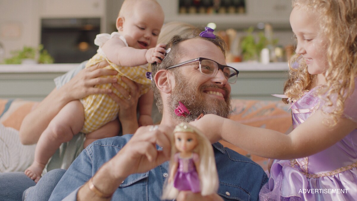 Man with hair clips in his beard playing with his two daughters