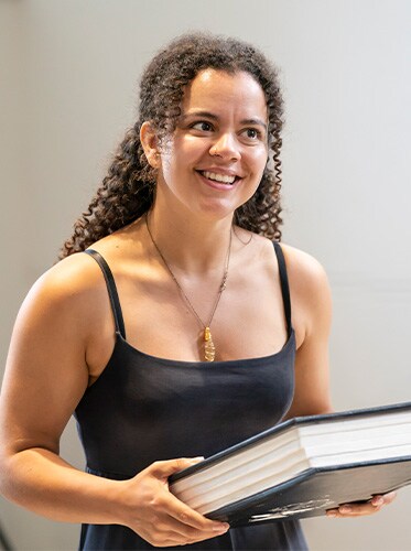 Courtney Stapleton smiling and holding a big book.