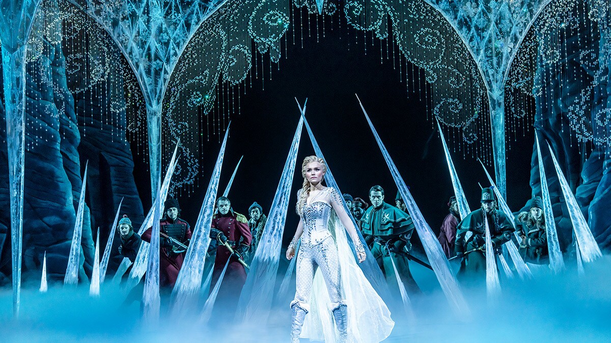 Elsa standing in a warrior position in front of armed men stopped by ice spikes.