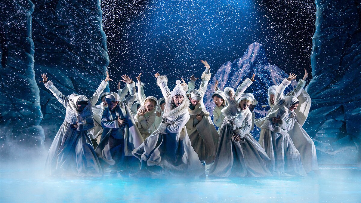 Frozen's ensemble on stage with snow and ice effects.