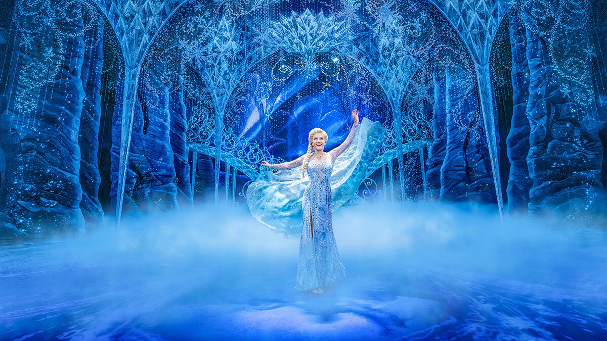 Elsa singing and dancing on stage against a misty, snowy background. 