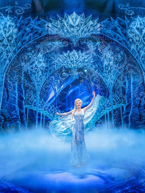 Elsa standing in front of her Ice Palace on stage
