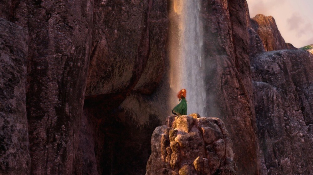 Merida on the top of a rocky cliff with a waterfall behind her