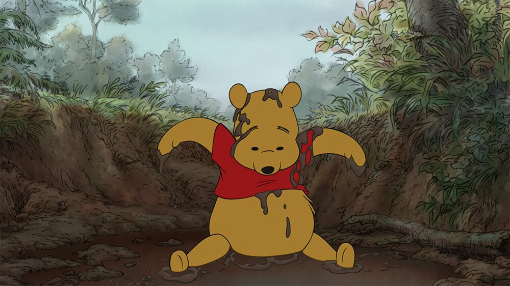 A muddy Winnie the Pooh sitting in mud