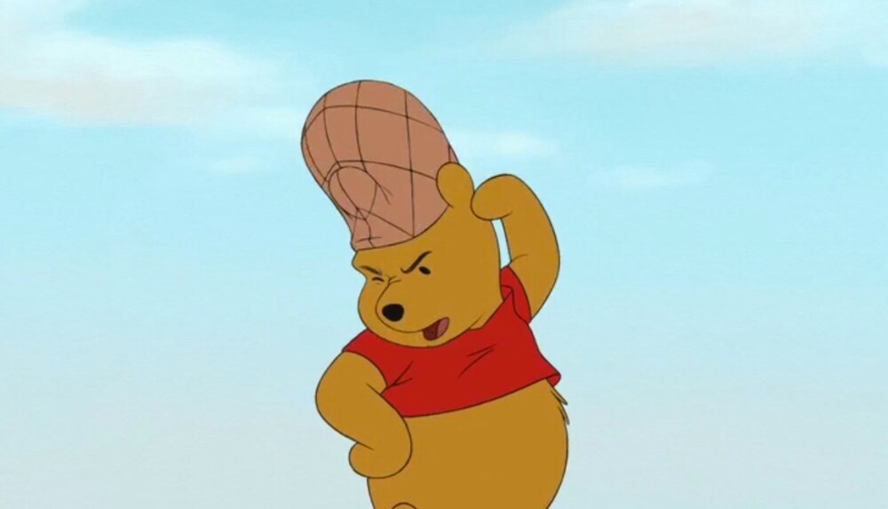 Winnie the Pooh concentrating with an oven mitt on his head