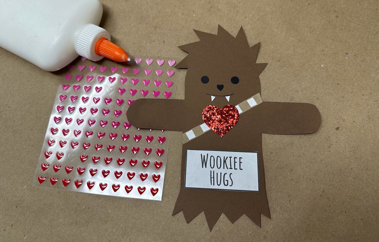 DIY Wookiee valentine in progress, with a Chewbacca-shaped card, glue, and stick-on hearts.