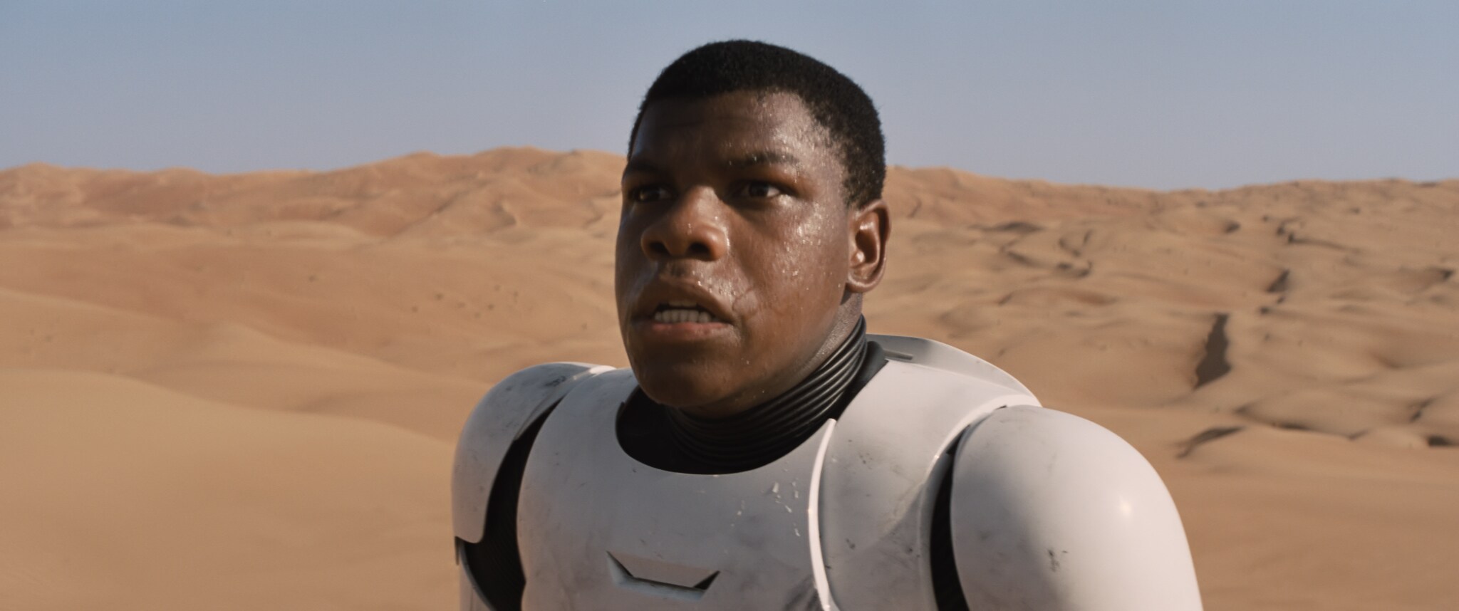 John Boyega as Finn in stormtrooper armor on Jakku. From the movie, "Star Wars: The Force Awakens."